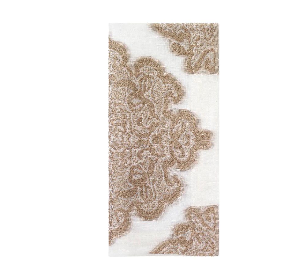 The Bodrum Castille Napkin Set of 4 - Sand features elegant white cloth napkins adorned with a detailed, textured beige floral pattern on one side, perfectly complementing other Castille table linens like coordinating napkins and table runners.