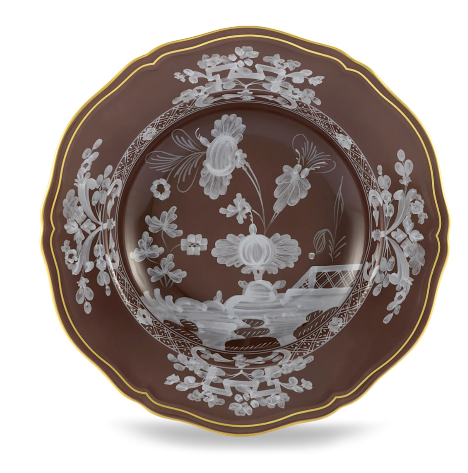 A decorative brown plate with scalloped edges, gold trim, and white floral designs from the Oriente Italiano Castagna collection by Ginori 1735, made in Italy.
