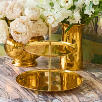 The Sinta 2 Tier Stand by Aerin rests on a marble surface, with gold vases of white and blush flowers in the background, creating an elegant and luxurious setting.
