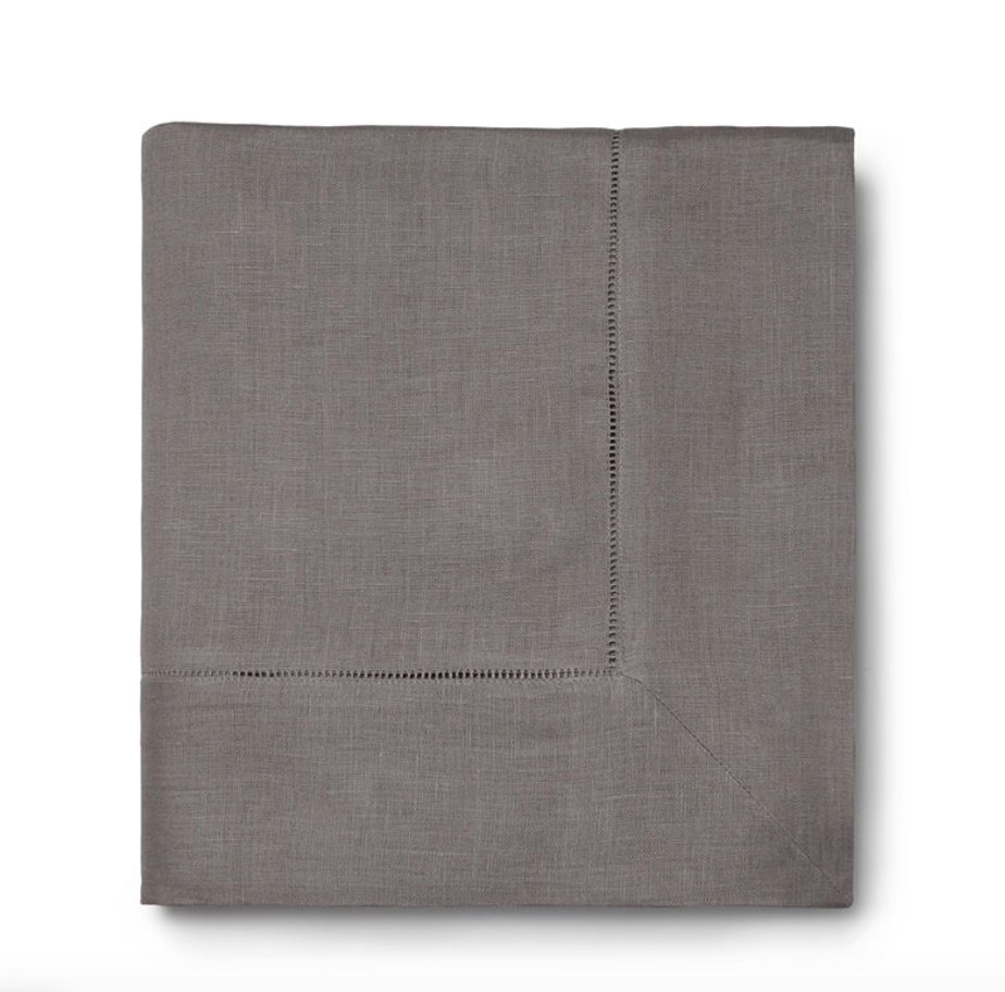 The Sferra Festival Tablecloth is a neatly folded, gray linen tablecloth with a hemstitch border detail, displayed on a white background.