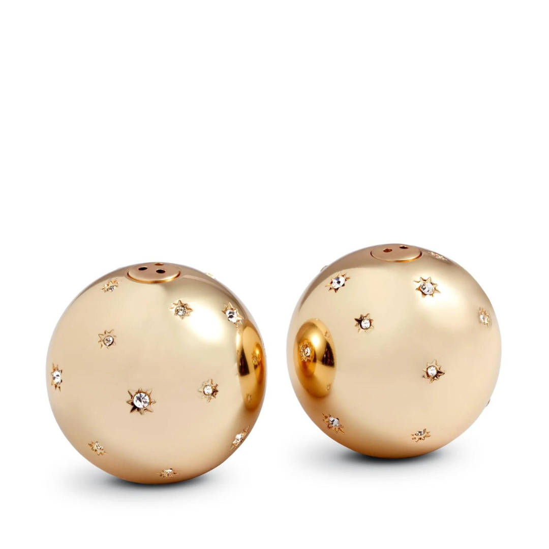Two gleaming, platinum, spherical salt and pepper shakers adorned with star-shaped patterns and Swarovski crystals from the Stars Spice Jewels Salt & Pepper Set by L'Objet sit side by side on a white background.