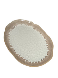 The Simon Pearce Burlington Dinnerware Bluff is an oval ceramic plate with a textured light grey center and a brown, irregular edge, offering an organic look inspired by natural stone.