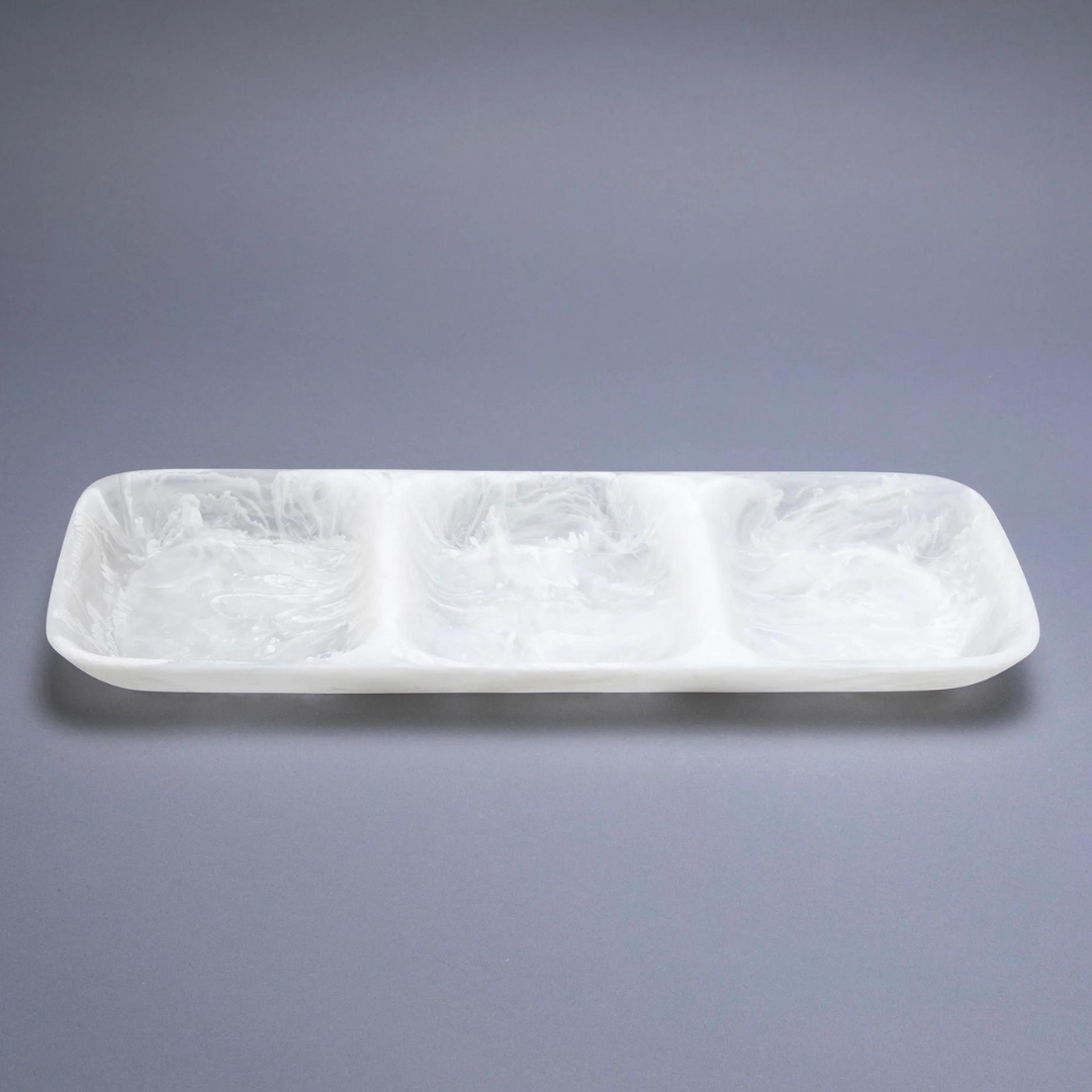 The Nashi Home Swirl Resin Classic 3 Section Tray is a rectangular white tray with three separate compartments, made from food-safe, marbled resin. Its shatter-resistant design is showcased on a plain gray surface.