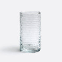 The Duncan Glassware Clear by Blue Pheasant is a hand-blown glass with a textured grid-like pattern, shown upright on a white surface and light gray background—ideal for everyday use.
