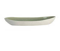 The Maguelone Cachemire Dinnerware by Jars - Rosenthal is a long, oval ceramic dish with a white exterior and light green interior. Shown from the side on a white background, this handmade piece is dishwasher safe for easy cleaning.