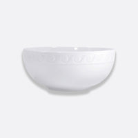 The Bernardaud Louvre Dinnerware features a plain white ceramic bowl with an embossed swirl rim, inspired by Renaissance French architecture, displayed on a light gray background.