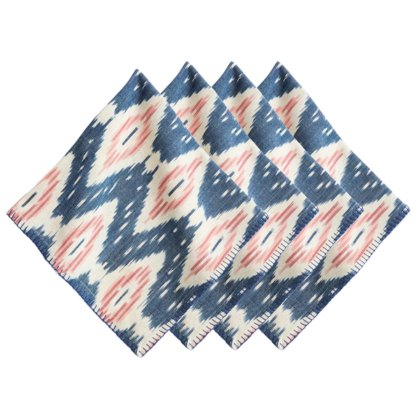 The Juliska Ikat Napkin Set of 4 features a blue, white, and blush-toned pattern, neatly arranged in a fan shape on a white background to evoke the relaxed elegance of island living.