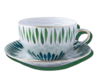 The Marie Daâge Allee de Cypres 5 teacup and saucer by Marie Daâge features hand-painted green and blue leaf patterns with gold accents, offering a luxurious porcelain tableware piece.