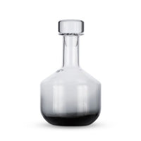 A Tom Dixon Tank Black Whiskey Decanter with a round stopper, wide base, and narrow neck is photographed against a plain white background.