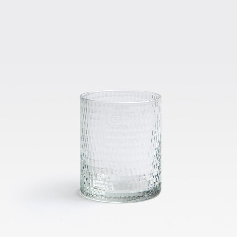 The Duncan Glassware Clear tumbler by Blue Pheasant, featuring a textured dimpled surface, sits empty on a white background—combining timeless bar style with everyday versatility.