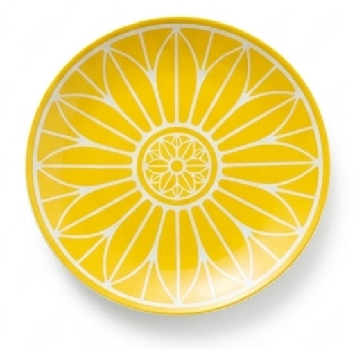 The Malmaison Riviera Dinnerware by Christofle features a round plate with a vibrant yellow and white geometric floral pattern, inspired by petals radiating from the center—ideal for French Riviera-style dining.