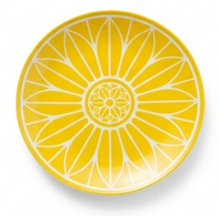 The Malmaison Riviera Dinnerware by Christofle features a round plate with a vibrant yellow and white geometric floral pattern, inspired by petals radiating from the center—ideal for French Riviera-style dining.