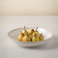 A Casafina Taormina Dinnerware White bowl, made in Portugal, holds eight speckled pears on a light surface with a simple pale background.