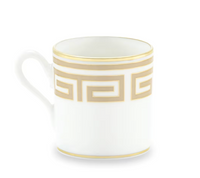 The Ginori 1735 Labirinto Dinnerware - Cashemire mug is a white porcelain mug with one handle, adorned with a gold Greek key pattern and gold trim, inspired by Gio Ponti's iconic design.