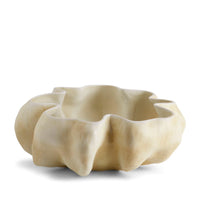 The Timna Bowl Latte by L'Objet features a cream-colored, sculptural porcelain form with a wavy, organic rim and a textured matte surface, evoking the look of hand-sculpted art.