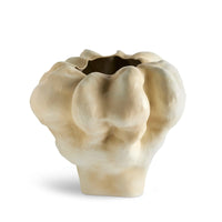 The Timna Latte Vase Short by L'Objet features a beige, irregular porcelain form with a wavy organic surface and uneven opening, recalling the mysterious landscapes of the Arava desert and cloud-like shapes.