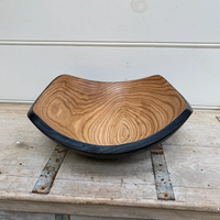 The Peterman Two Toned Square Oak Wood Bowl features a handcrafted design with natural wood grain, a light interior, and dark rim and edges. This food-safe bowl adds rustic charm to any table setting.