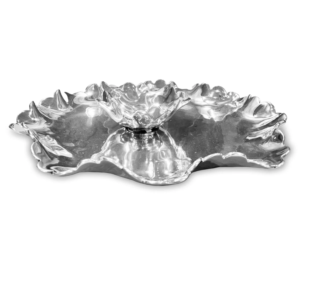 The Beatriz Ball Vento Colette Chip & Dip is a shiny silver cast metal serving dish with an irregular wavy edge and a small matching center bowl, artfully designed to resemble a flower or leaf.