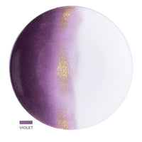 The Marie Daâge Horizon Gold Dinnerware features a round, hand-painted porcelain plate with a gradient from deep violet to white and a gold-speckled stripe, plus the "VIOLET" label and color swatch in the bottom left corner. Brand: Marie Daâge.