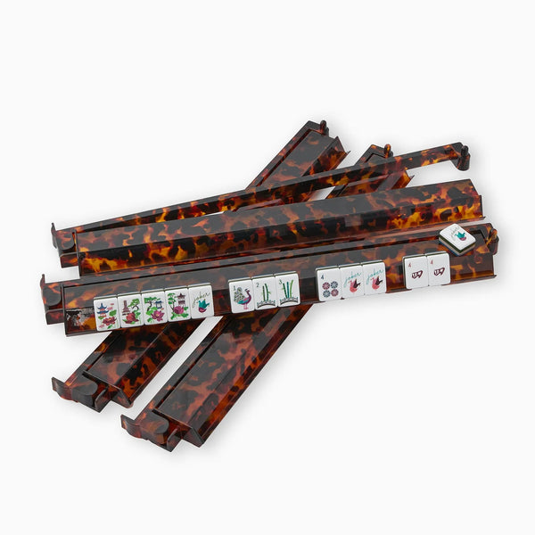 Five tortoiseshell-patterned Mahjong Rack & Pusher Sets by Oh My Mahjong are stacked, one displaying mahjong tiles and dice—perfect Game Night Accessories for any pusher set fan. The tiles show classic mahjong symbols.