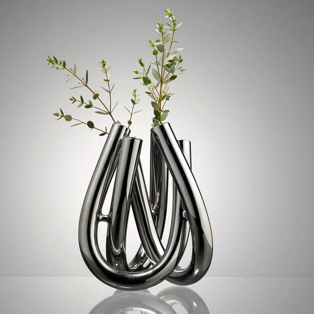 The Trui Vase by Rosenthal features a complex intertwined design and lustrous PVD coating, perfectly displaying delicate green branches.