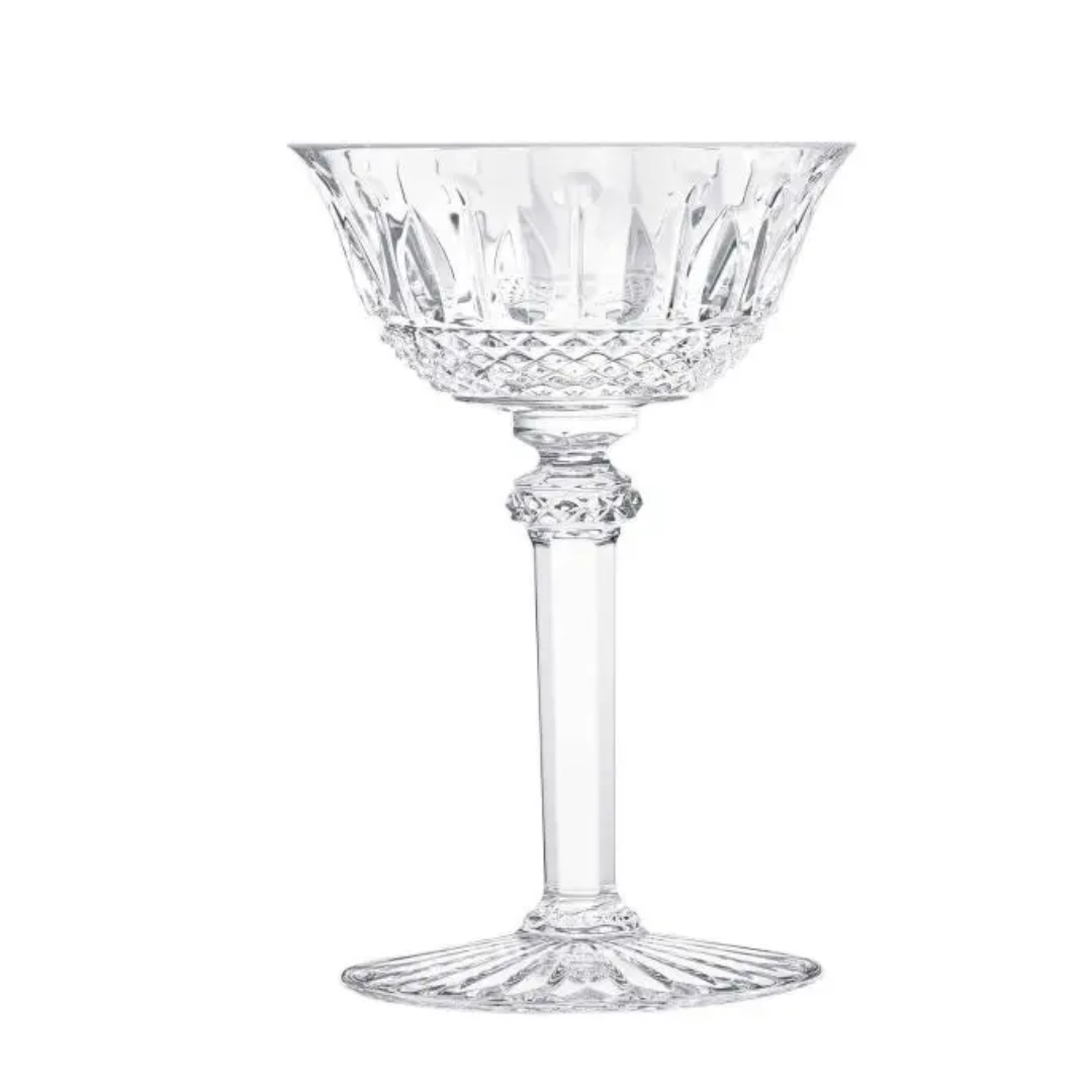 The Saint-Louis Tommy Stemware features a clear, intricately cut crystal coupe glass with a decorative bowl, faceted stem, and flared base—an elegant luxury piece displayed on a white background.