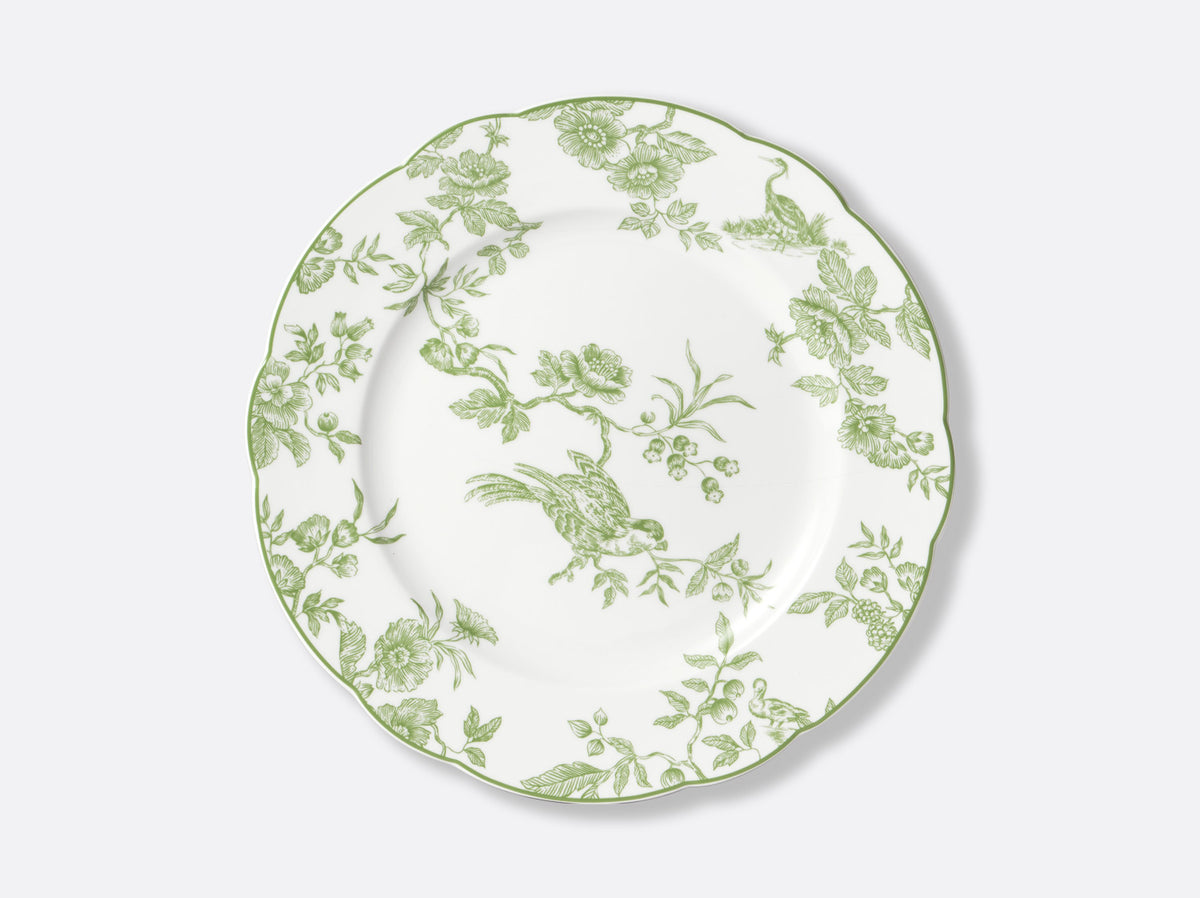 The Albertine Dinnerware by Bernardaud is a white porcelain plate with scalloped edges, adorned with ornate green floral and bird motifs inspired by classic toile de Jouy—a poetic nod to iconic Bernardaud design.