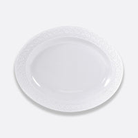 The Bernardaud Louvre Dinnerware features an empty white oval plate with an embossed rim, inspired by Renaissance elegance and French architecture—a refined piece for elegant white table settings.