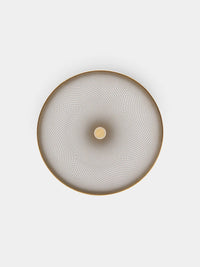 A round Oskar Dinnerware piece by Raynaud, featuring gold edges and a concentric, spiraling geometric design with a small central circle, reminiscent of elegant Limoges porcelain, viewed from above against a plain white background.