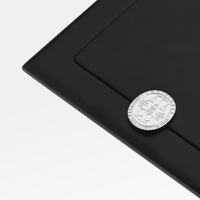A Christofle Fidelio Silver Plated Frame 7x9.5 in sleek black features a silver coin on its corner, set against a plain white background.