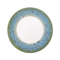 The Nymphea Dinnerware plate by Jaune De Chrome features Limoges porcelain, a plain white center, and a wide rim with an irregular blue and green speckled artistic design.