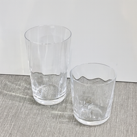 Two clear Optic Everyday Cups by Gary Bodker—one tall, one short—sit on a textured light gray surface with a plain white background.