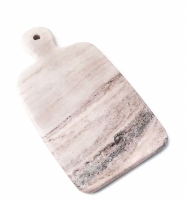 The Simon Pearce Marble Board Medium is a rectangular cutting board with rounded edges and a handle with a small hole. Displayed on a white background, its marble surface features light pinkish and gray natural veining.