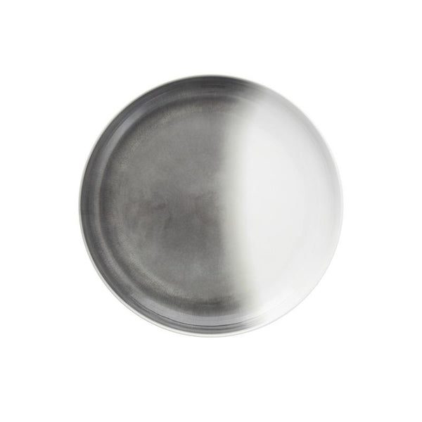 The Fortessa La Cotera Melamine Dinnerware Gray plate features a round, metallic look with a matte gradient—half dark, half light. Stylish and dishwasher safe, this durable piece is perfect for modern dining and is set against a plain white background.
