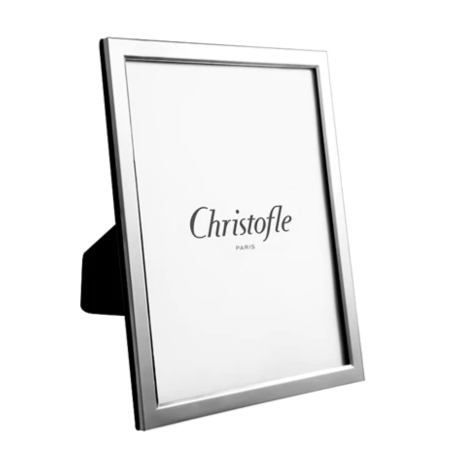 The Christofle Uni Picture Frame features a sleek, smooth silver border and stands at an angle. Its elegant, engravable design makes it perfect for showcasing special memories. The center displays "Christofle Paris" on a white background.