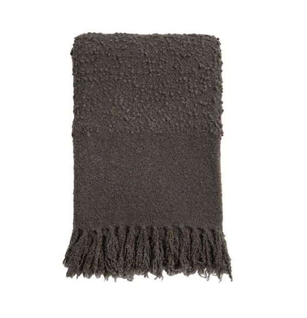 The Murphy Throw - Midnight by Pom Pom At Home is neatly folded, showcasing its fluffy bouclé texture and thick fringe tassels along one edge, set against a plain white background.
