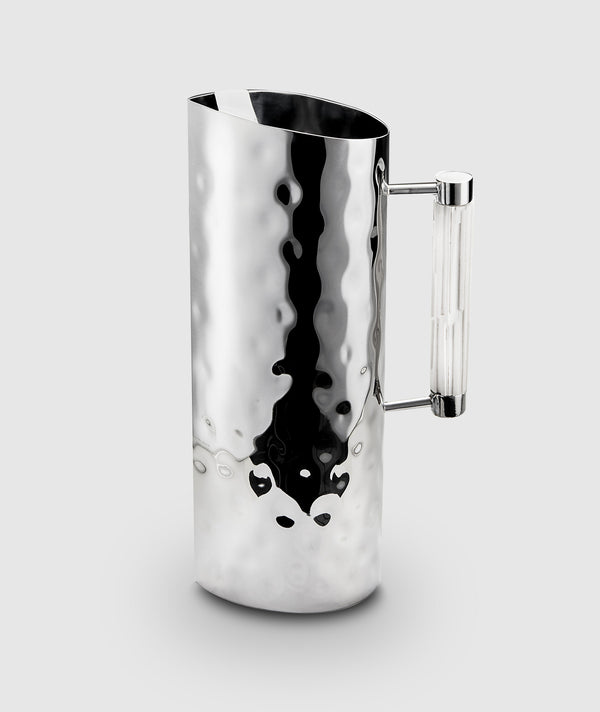 The Mary Jurek Tundra Resin Handle Pitcher - White features a tall, cylindrical, hammered stainless steel body with a reflective finish and a white resin handle, set against a light gray background.