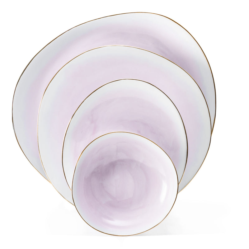 The Galette Dinnerware set by Molecot includes four pastel lavender plates and bowls with irregular round shapes, hand-painted porcelain, subtle gold rims, and a glossy finish—each piece stacks neatly inside the next.