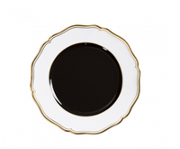 A round Mazurka Dinnerware Or Black plate by Raynaud, featuring a scalloped white rim, gold trim, and glossy black center, is displayed from above on a white background—showcasing refined French craftsmanship.