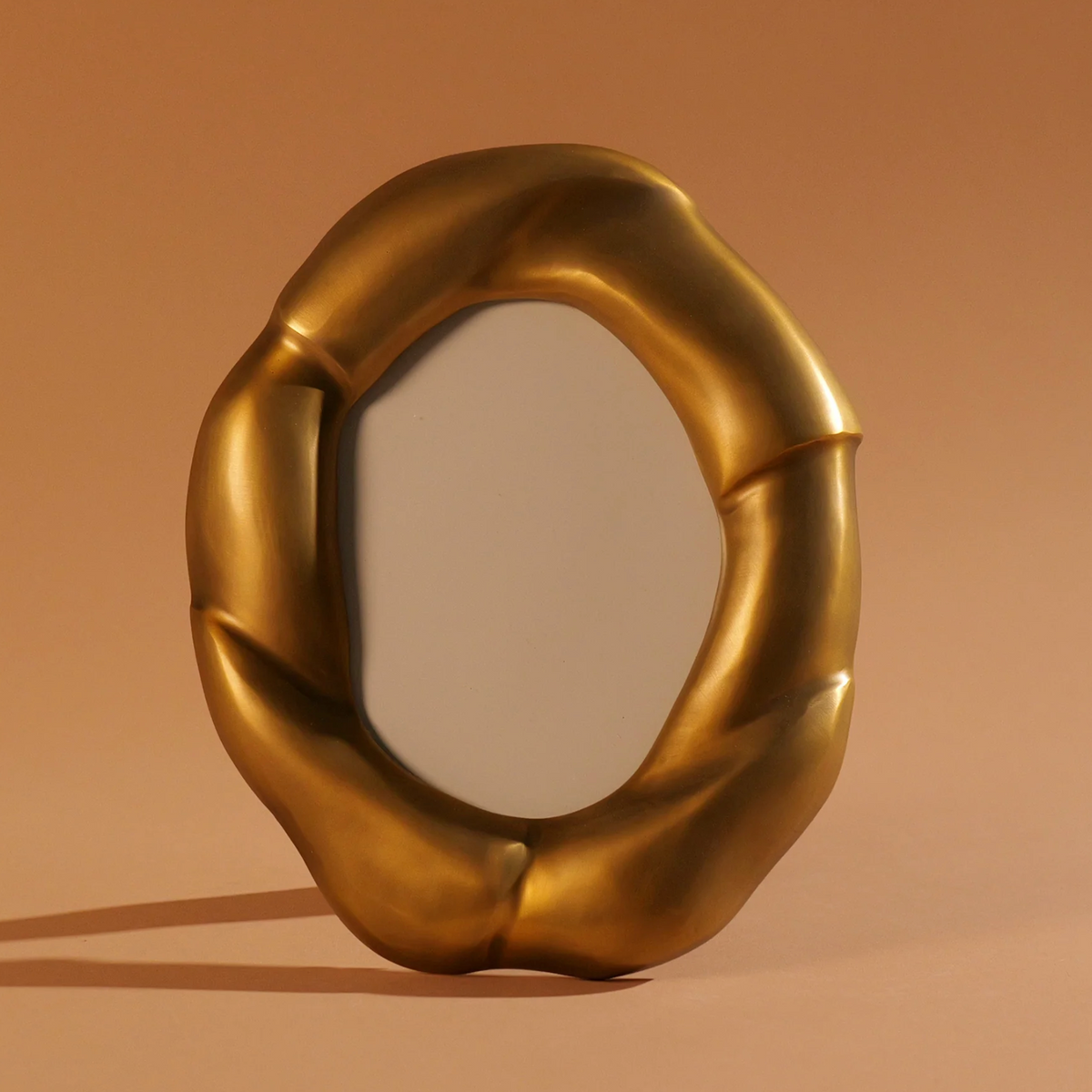 The Julie Oval Frame Brass - by Dumae features a gold, bamboo-inspired twisted frame—ideal for pairing with elegant picture frames or gifting—shown against a plain brown background.