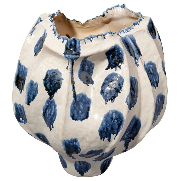 The Moncler Blue Vase by Jamie Young is a white ceramic piece with an uneven, jagged rim, featuring large blue reactive glaze spots and drips for a handcrafted, organic look.