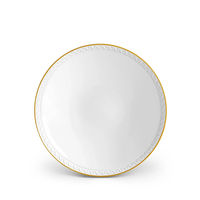 The Neptune Gold plate by L’Objet is a round white porcelain piece featuring a subtle swirl near the rim and a 24k gold edge, shown on a plain white background.
