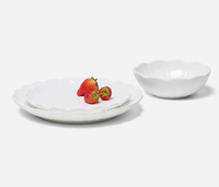Three Iris Melamine dishes by Blue Pheasant are arranged on a white surface: two stacked plates with three strawberries on top and a matching bowl nearby.