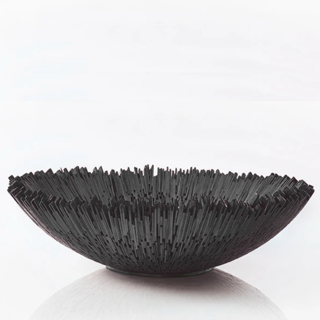The Boracay Centerpiece Bowl by Lily Juliet is a handcrafted, round black bowl with jagged vertical spikes along the rim, creating a modern sculptural look that serves as a striking decorative centerpiece.