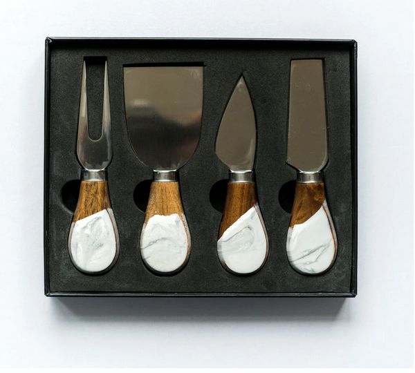 Elevate your cheese board with the Lynn & Liana Serveware Painted Cheese Knives s/4 - White Marble, featuring four stainless steel knives with marble design and wood handles, all in a sleek black box with foam insert.