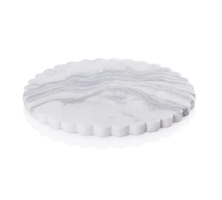 The Zodax Dolly Marble Cheese Board features a round, white marble surface with subtle gray veining and elegant scalloped edges, showcased on a clean white background.