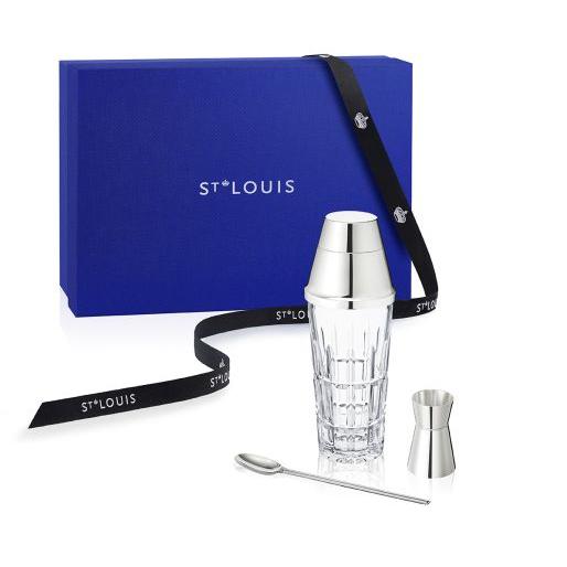 The Manhattan Mixology Set by Saint-Louis/Hermes, including a crystal cocktail shaker, jigger, and stirring spoon, is displayed before a blue Saint-Louis gift box adorned with a black ribbon bearing the brand name.