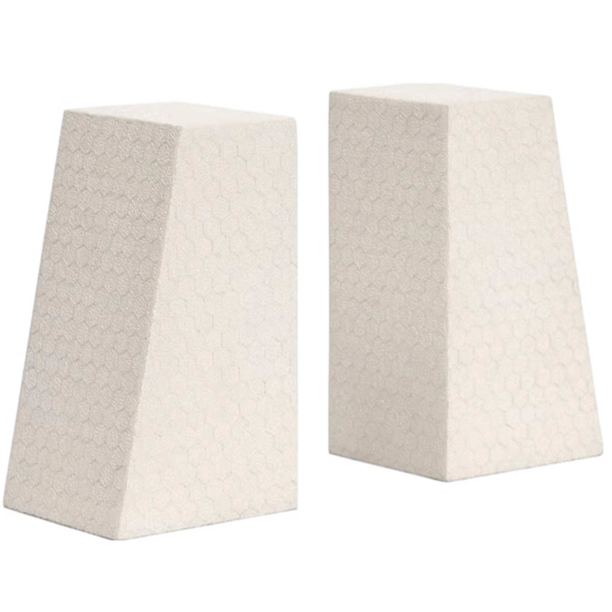 Two beige, trapezoidal Rene Faux Shagreen Bookends by Made Goods stand side by side, their subtle hexagonal texture and architectural edges highlighted against a white background.