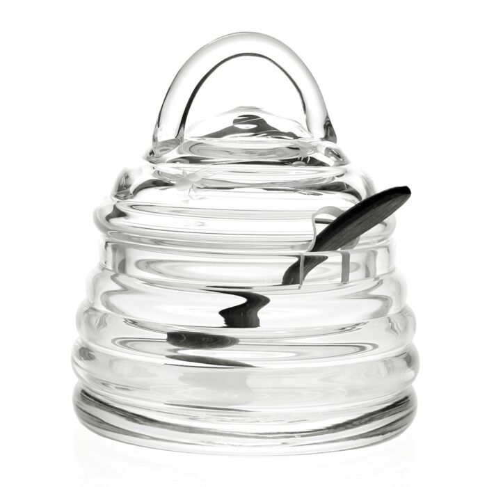 The William Yeoward Honeybee Honey Jar & Spoon is a handmade crystal beehive-shaped jar with lid, featuring a slot for the included matching spoon that rests inside.