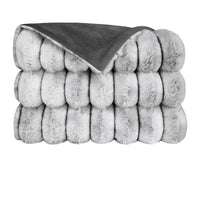 The Summit Throw by D.V. KAP / Canaan Company features a thick, folded gray faux fur texture on one side and smooth dark gray fabric on the other, shown against a white background.